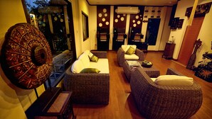 A modern living room with wicker furniture, a large wall clock, and a view of the outside. - Ploykhumthong Boutique Resort (Bangkok)