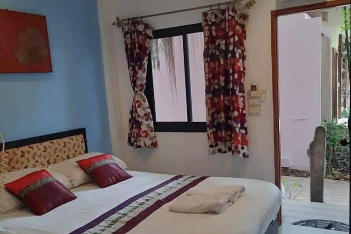 Un dormitorio con cama, cortinas, una ventana y un equipo de aire acondicionado.