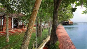 A riverside walkway with a wooden structure and a floating house. - Saro Lake County (Kottayam)