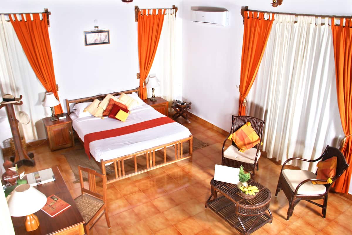 A hotel room with a bed, two chairs, a small table, and a lamp.