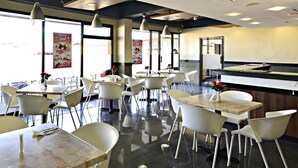 A restaurant with white chairs and tables, a counter, and large windows. - Express Inn - Cebu Hotel (Cebu City)