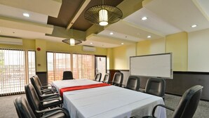 A conference room with a long table, black chairs, a whiteboard, and a red accent on the table. - Express Inn - Cebu Hotel (Cebu City)
