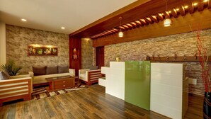 A modern living room with a sofa, chairs, a coffee table, and a decorative wall with a stone pattern. - Periyar Nest Resorts (Peermade)
