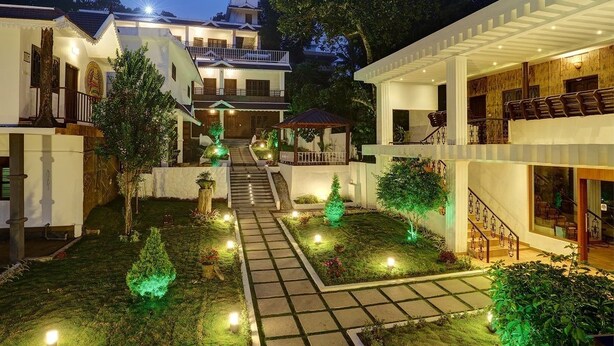 A courtyard with a central pathway, surrounded by buildings with balconies and large windows. - Periyar Nest Resorts (Peermade)