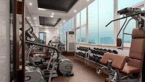 A modern gym with various exercise equipment, large windows, and a city view. - Golden Tulip Gurgaon - Sector 29 (Gurugram)