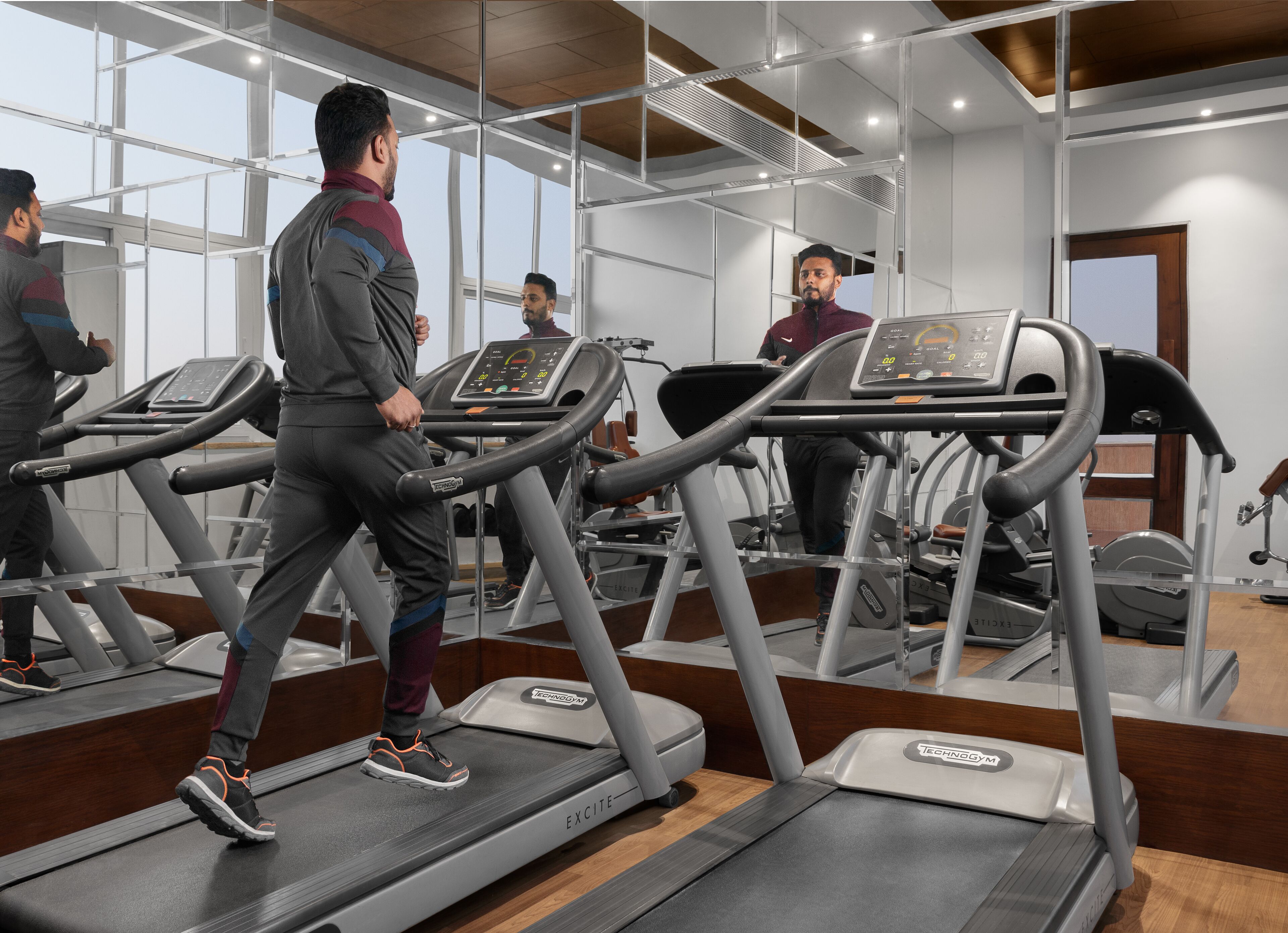 A gym with multiple treadmills, mirrored walls, and a modern design.
