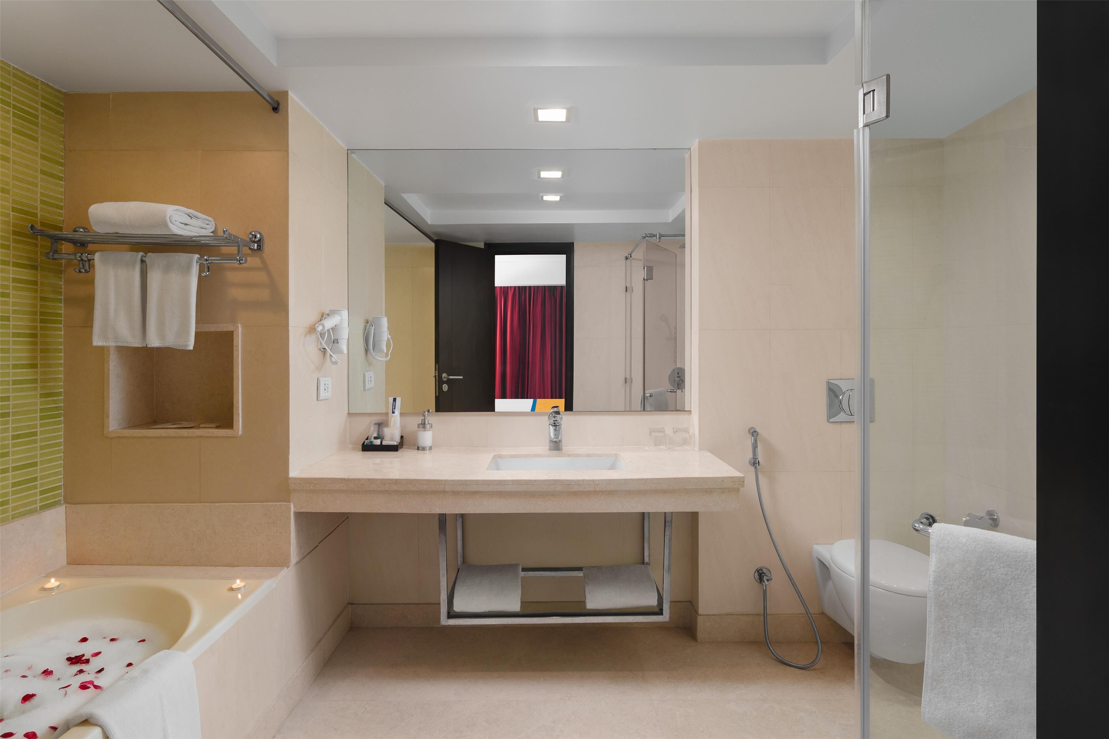 A modern bathroom with a bathtub, shower, and toilet.