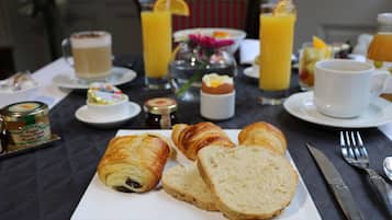 Una mesa de desayuno con cruasanes, pan y una taza de café.