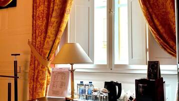 A hotel room with a desk, a lamp, a menu, and a window with curtains.