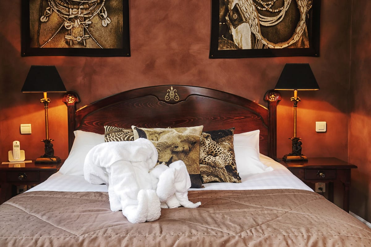 A hotel room with a large bed, two nightstands, a telephone, and two lamps.