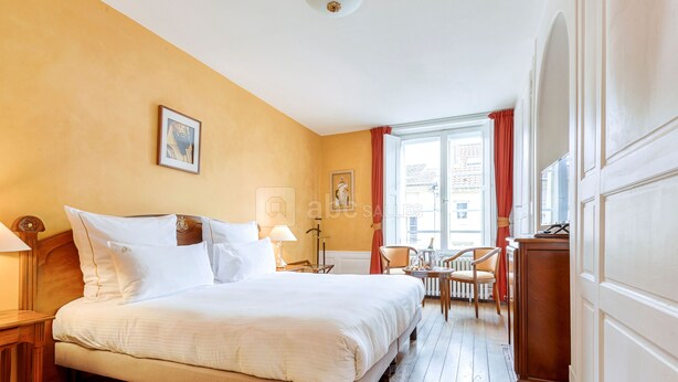 Habitación de hotel con una cama grande, un escritorio, una silla y una ventana con cortinas.