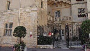 Un bâtiment historique doté d’une cour intérieure, d’une façade en pierre et d’une entrée fermée par un portail.