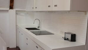 A small kitchen with white cabinets, a sink, and a toaster. - Rembrandtplein B&B (Amsterdam)