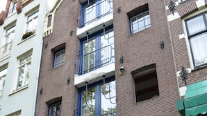 A multi-story brick building with a blue door, potted plants, and a visible apartment number. - Rembrandtplein B&B (Amsterdam)