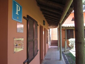 A corridor with a blue parking sign, wooden shutters, and a tiled floor. - Posada El Camino (Almonaster la Real)