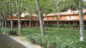 A courtyard with a tiled-roof building, surrounded by trees and a stone pathway. - Posada El Camino (Almonaster la Real)