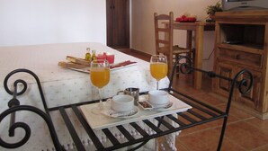 A dining table with breakfast items, two glasses of orange juice, and a television in the background. - Posada El Camino (Almonaster la Real)