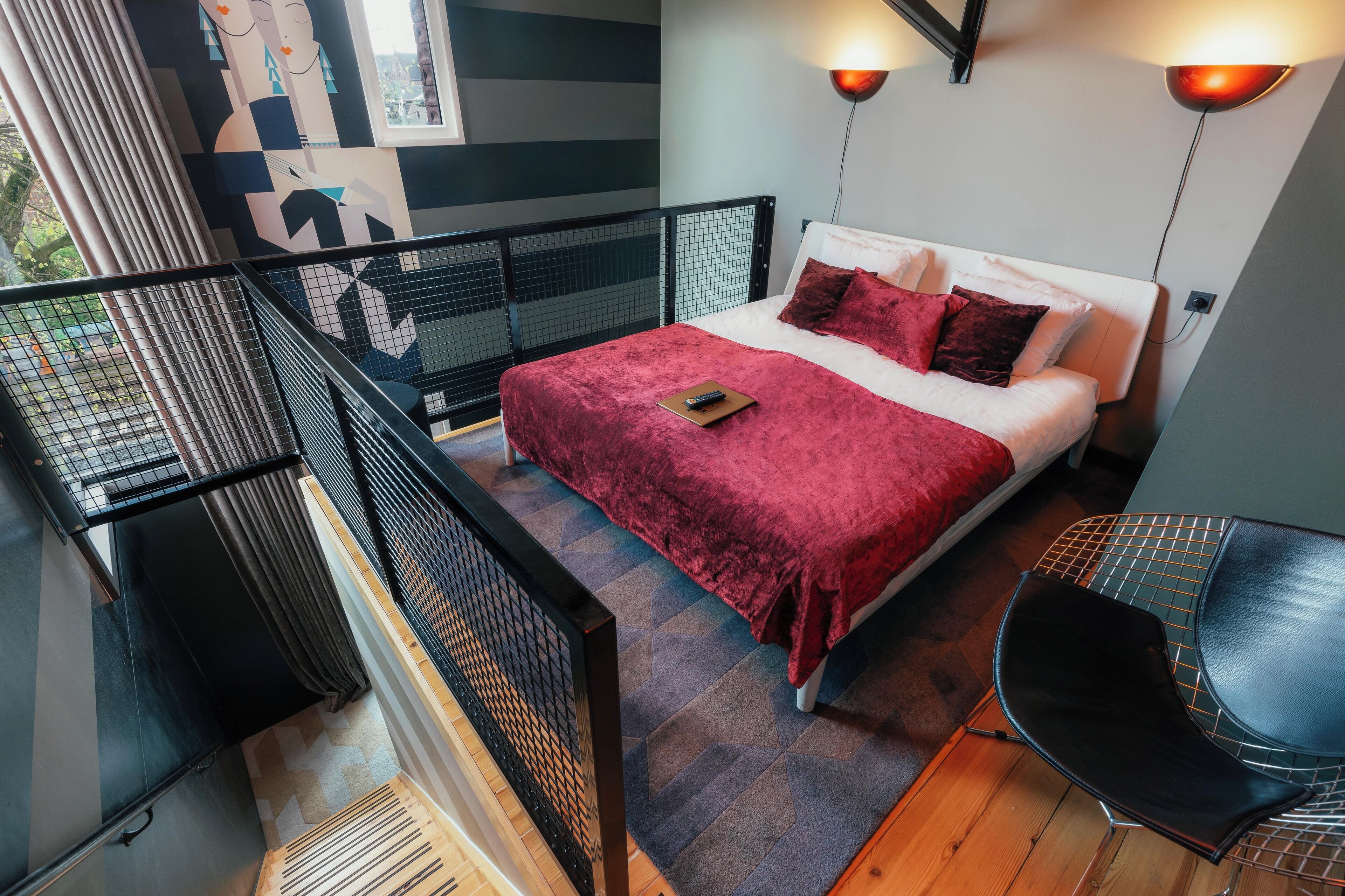Une chambre moderne avec un grand lit, une petite table et un balcon doté d’une balustrade.