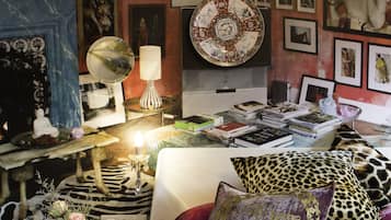 Una habitación con una cama, libros y varios objetos decorativos sobre estantes y mesas.