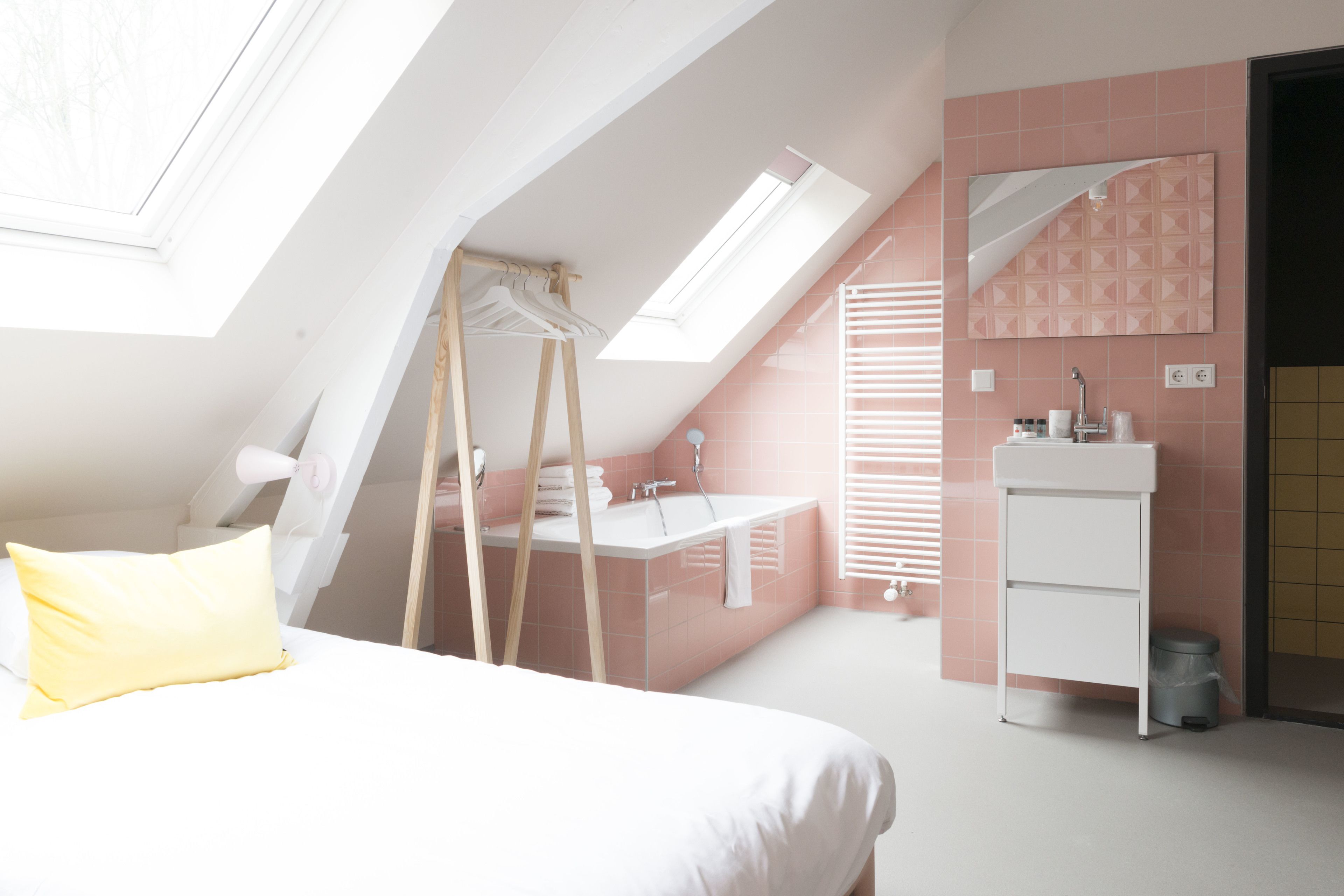 Un dormitorio con tragaluz, una cama, un escritorio y un baño con lavabo y espejo.