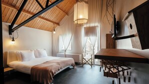 Un dormitorio moderno con cama, escritorio y lámpara colgante.