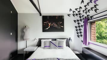 Relax in a stylish room with a neatly made bed, side table, and large window offering a view of lush greenery.