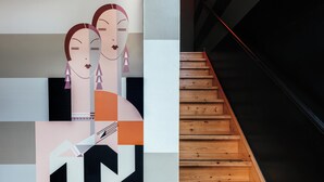 Un interior moderno con una obra de arte abstracta geométrica y una escalera de madera.