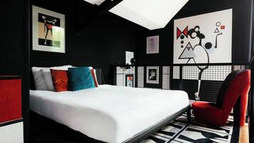 Un dormitorio moderno con una cama grande, una silla roja y arte abstracto en la pared.