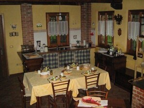 A dining area with two tables set for meals, a kitchen area with a counter and various kitchen items, and a brick wall with decorative elements.