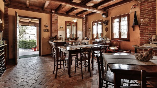 A rustic kitchen with wooden beams, a large dining table, and a brick wall. - Agriturismo Borg da Ocjs (Cormons)