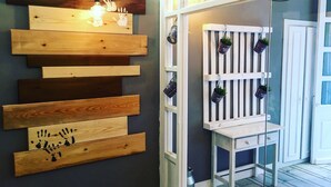 A room with a wall-mounted wooden shelf with handprints and a white cabinet with potted plants. - Hostal Le vintage (Ávila)