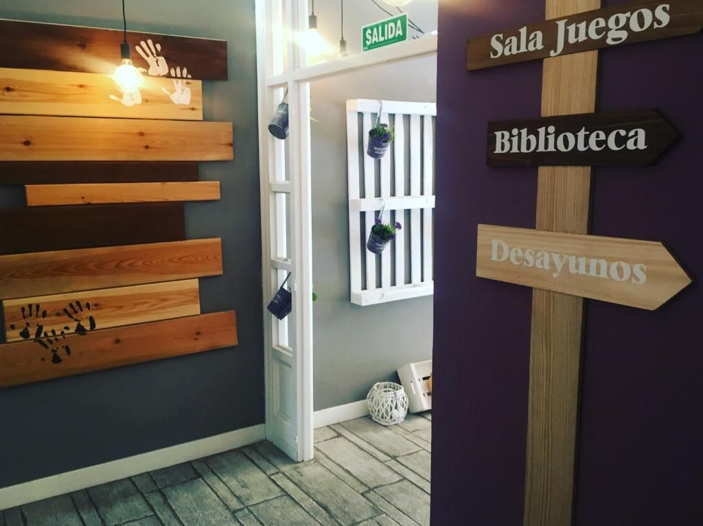 Un pasillo con señales indicativas para 'Sala Juegos', 'Biblioteca' y 'Desayunos'.