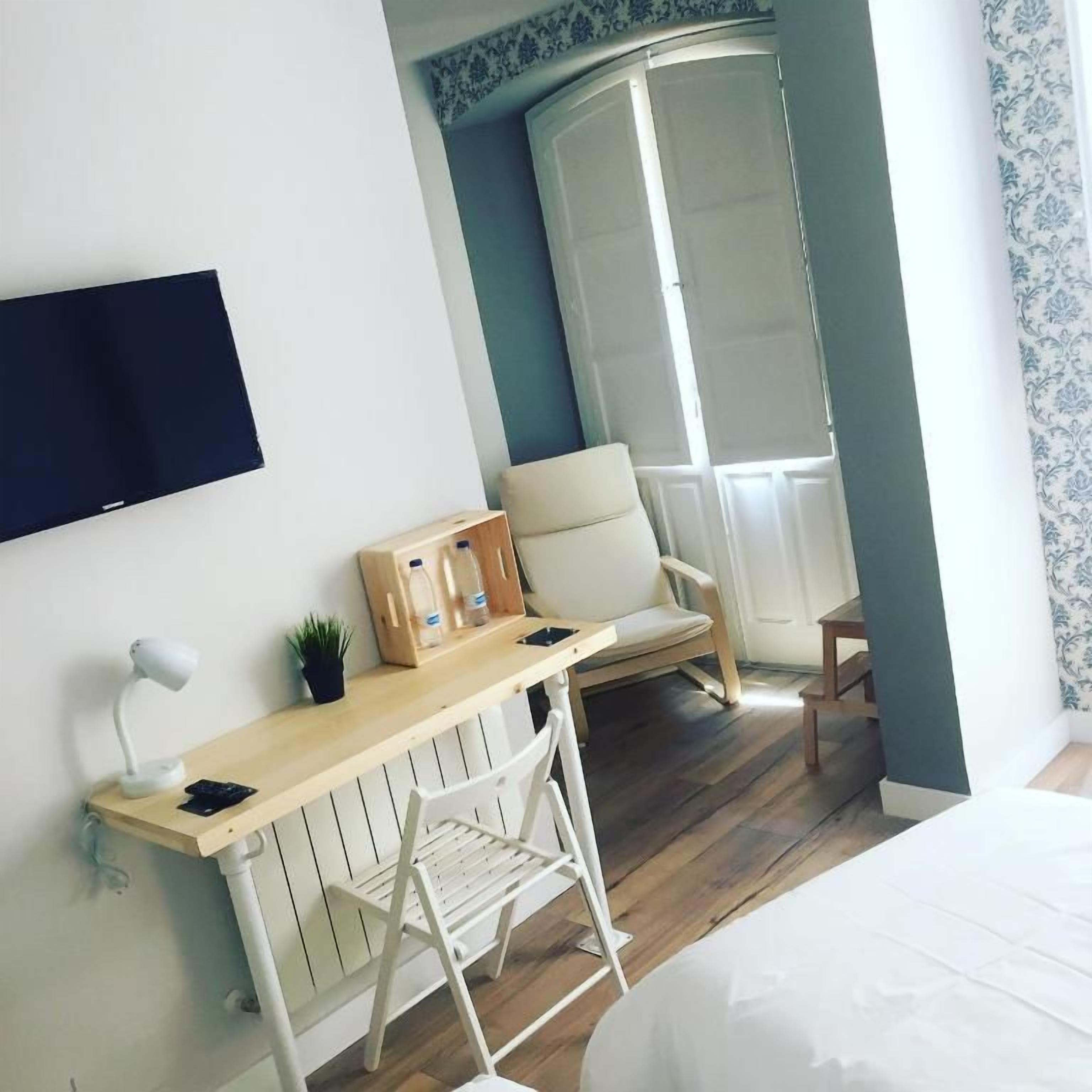 A hotel room with a bed, a desk with a chair, a television, and a wardrobe.
