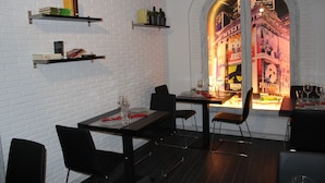 A restaurant with brick walls, black chairs, and tables set for dining. - Hostal Le vintage (Ávila)