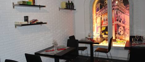 A restaurant with brick walls, black chairs, and tables set for dining.