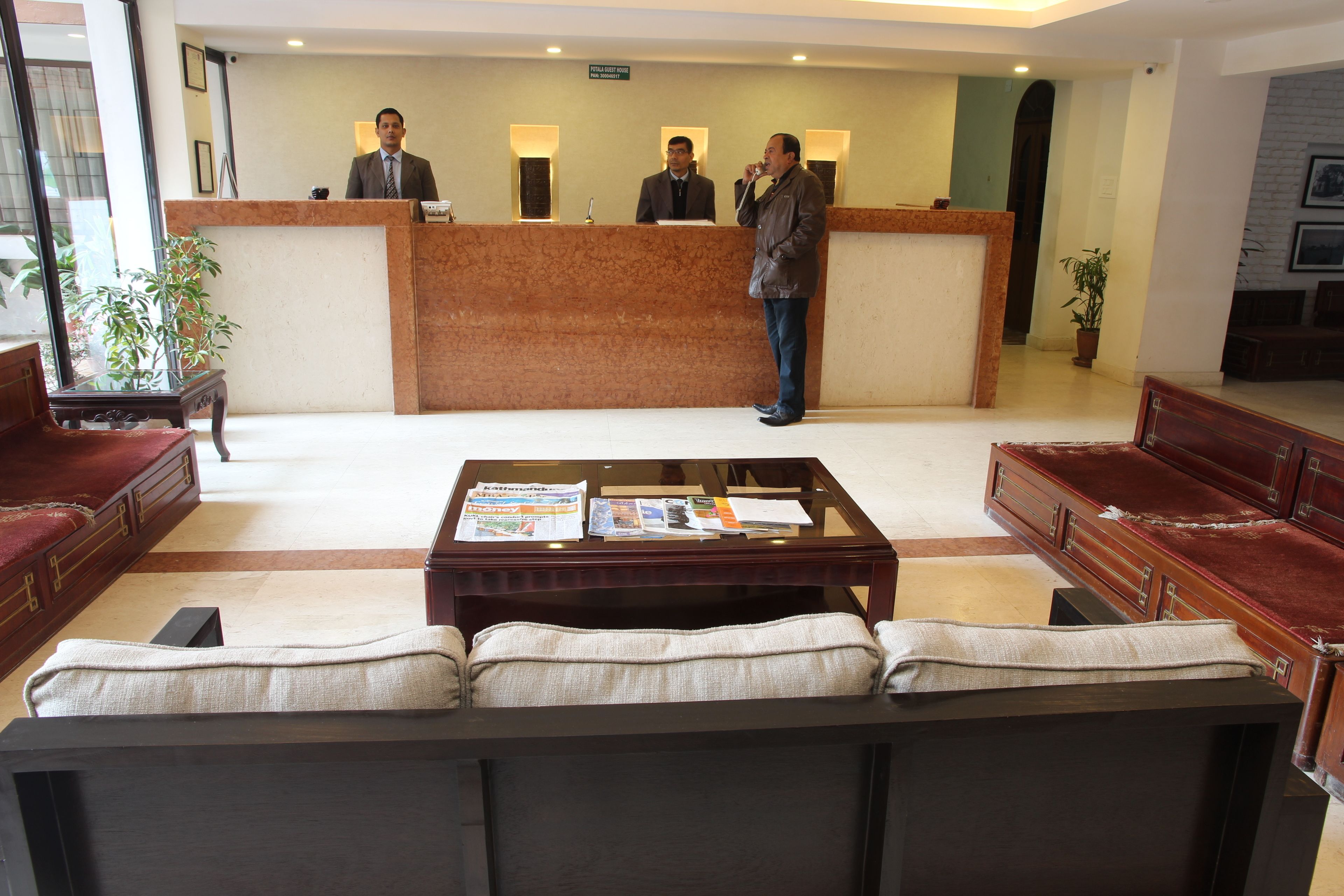 A reception area with a marble counter, two receptionists, a sofa, and a coffee table with magazines.
