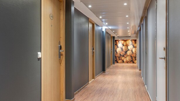 Pasillo con puertas de madera, numeradas 210, que dan a las habitaciones.