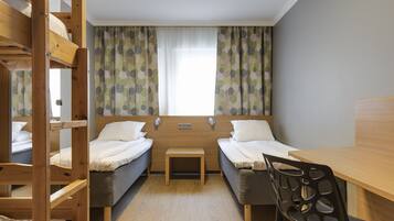 A compact room with two single beds, a small table, a bunk bed, and a wooden desk.