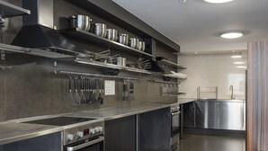 Una cocina moderna con electrodomésticos de acero inoxidable, una encimera amplia y utensilios colgantes.