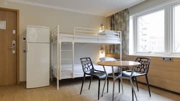 Habitació amb lliteres, nevera, taula i dues cadires.