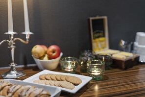 Una mesa con un plato de galletas, un bol de fruta y velas.