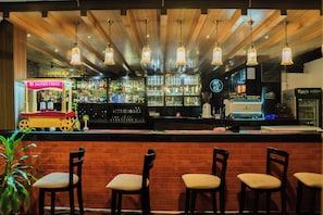 A bar area with wooden ceiling, hanging lights, and a bar counter with a display case.
