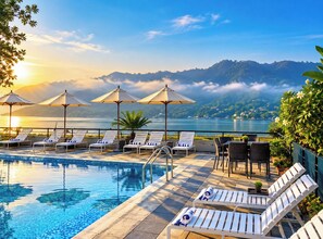 A poolside area with lounge chairs, umbrellas, and a view of a lake and mountains. - Waterfront Resort by KGH Group (Pokhara)