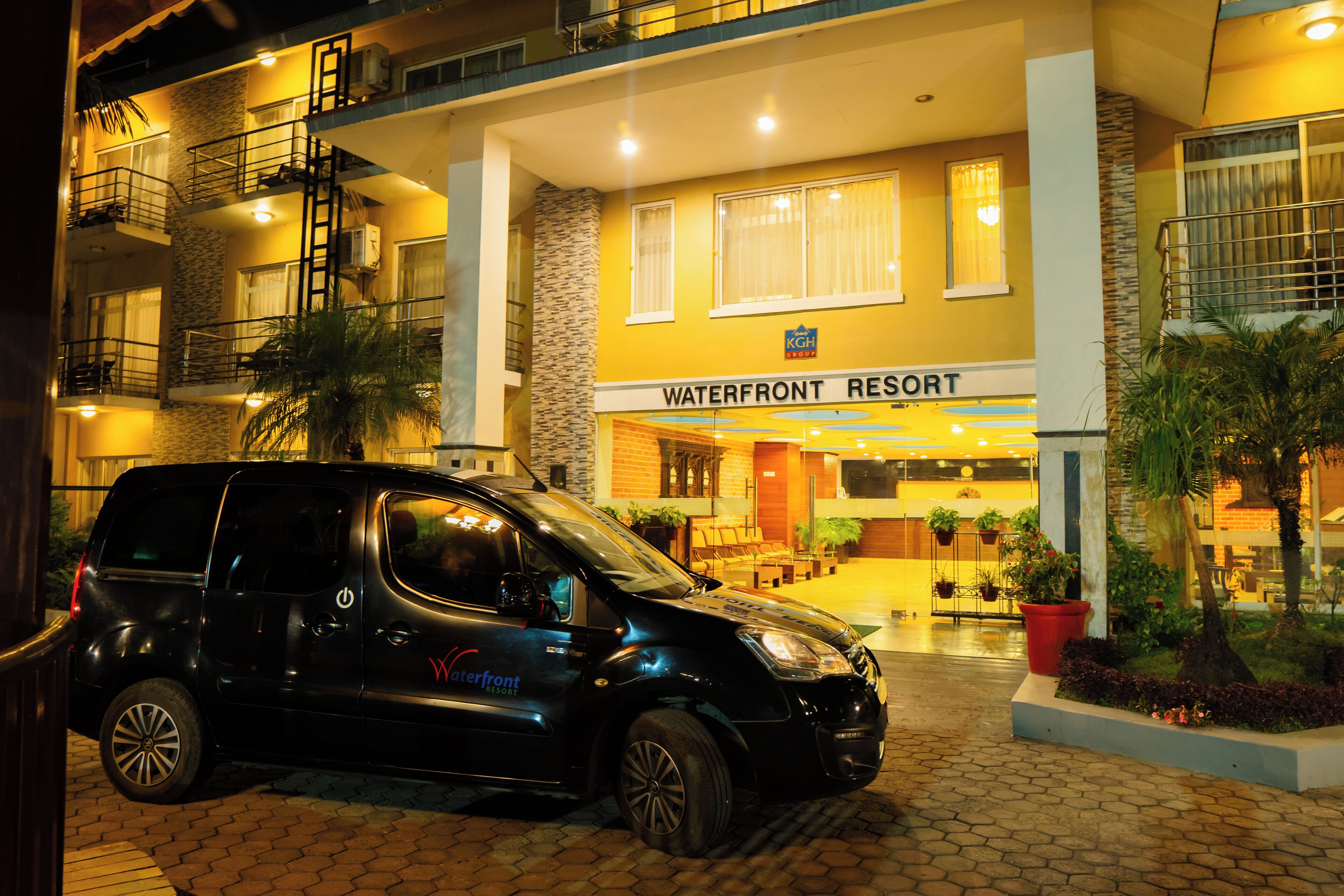 Un coche negro estacionado frente a un edificio con la leyenda 'Waterfront Resort'.