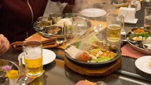 A dining table with various dishes, utensils, and a beer mug. - Waterfront Resort by KGH Group (Pokhara)