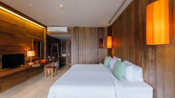 A modern hotel room with a wooden panel wall, a large bed with white bedding, a flat-screen TV, a desk with a lamp, and a wooden bench.