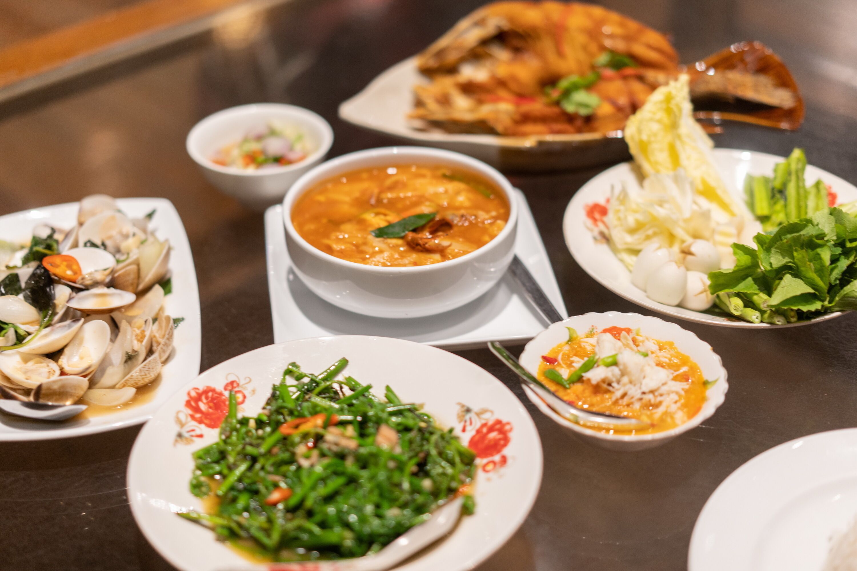 A variety of dishes on a table, including seafood, vegetables, and a bowl of soup.