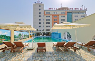 A hotel pool area with lounge chairs and umbrellas, a mural, and a building with the name "HOANG SOM PEACE HOTEL".