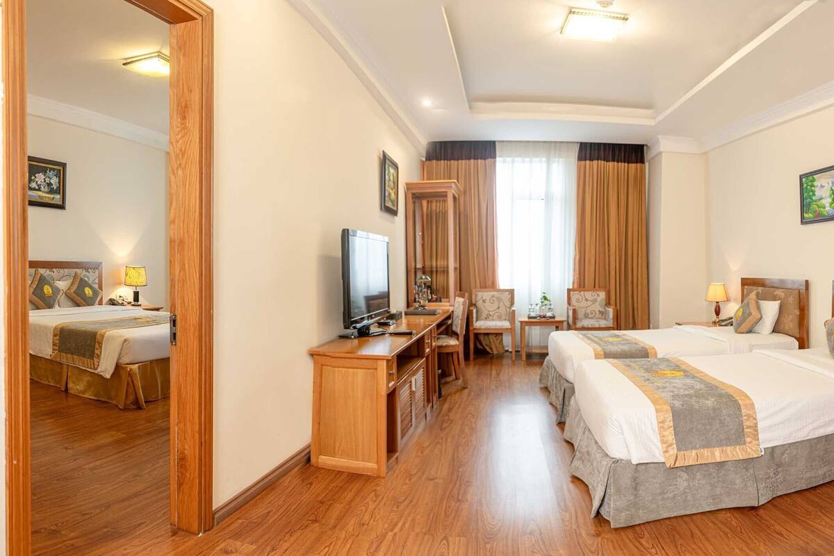 Ein Hotelzimmer mit zwei Betten, einem Schreibtisch, einem Fernseher und einem Spiegel.