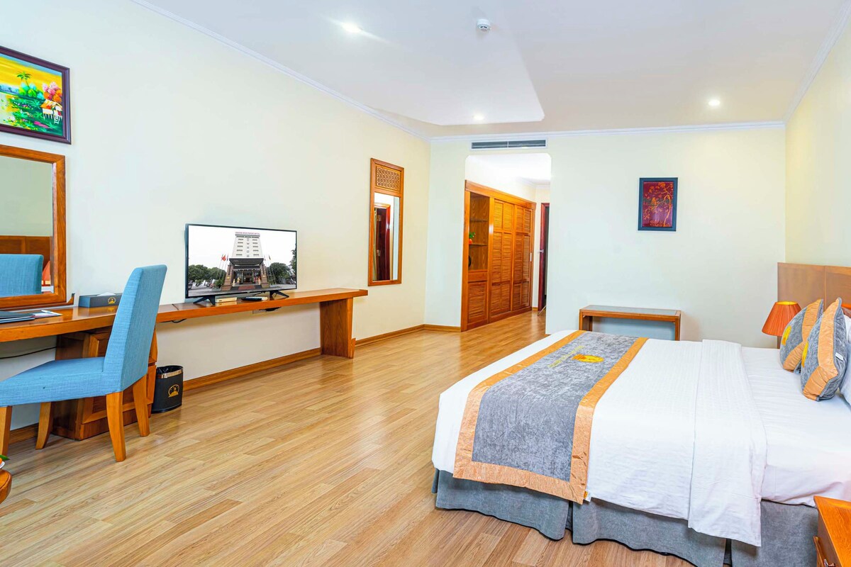 Habitación de hotel con cama, escritorio, silla y televisor.
